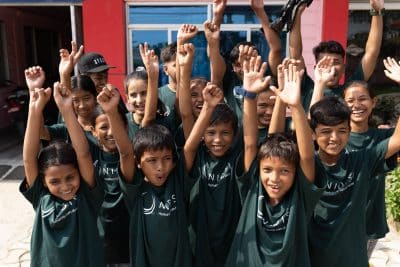 Eine Schulklasse aus Nepal, die jubelnd ihre Arme in die Luft heben.