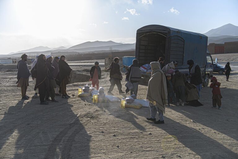 Ein Feld in Afghanistan, auf dem einige Menschen laufen und ein LKW steht.