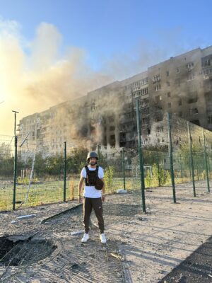 Serkan Eren vor einem brennenden Haus in der Ukraine nach einem Raketenangriff.
