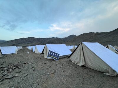 Auf einem weiten Feld in Afghanistan stehen viele weiße Zelte. Auf einem ist das Logo von STELP zu erkennen.