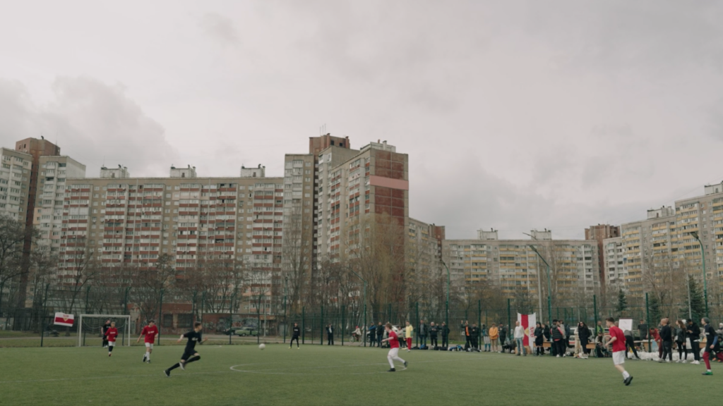 Menschen spielen Fußball in der Ukraine neben grauen Hochhäusern