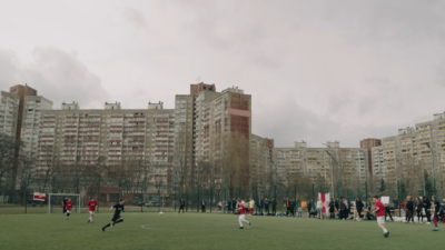 Menschen spielen Fußball in der Ukraine neben grauen Hochhäusern