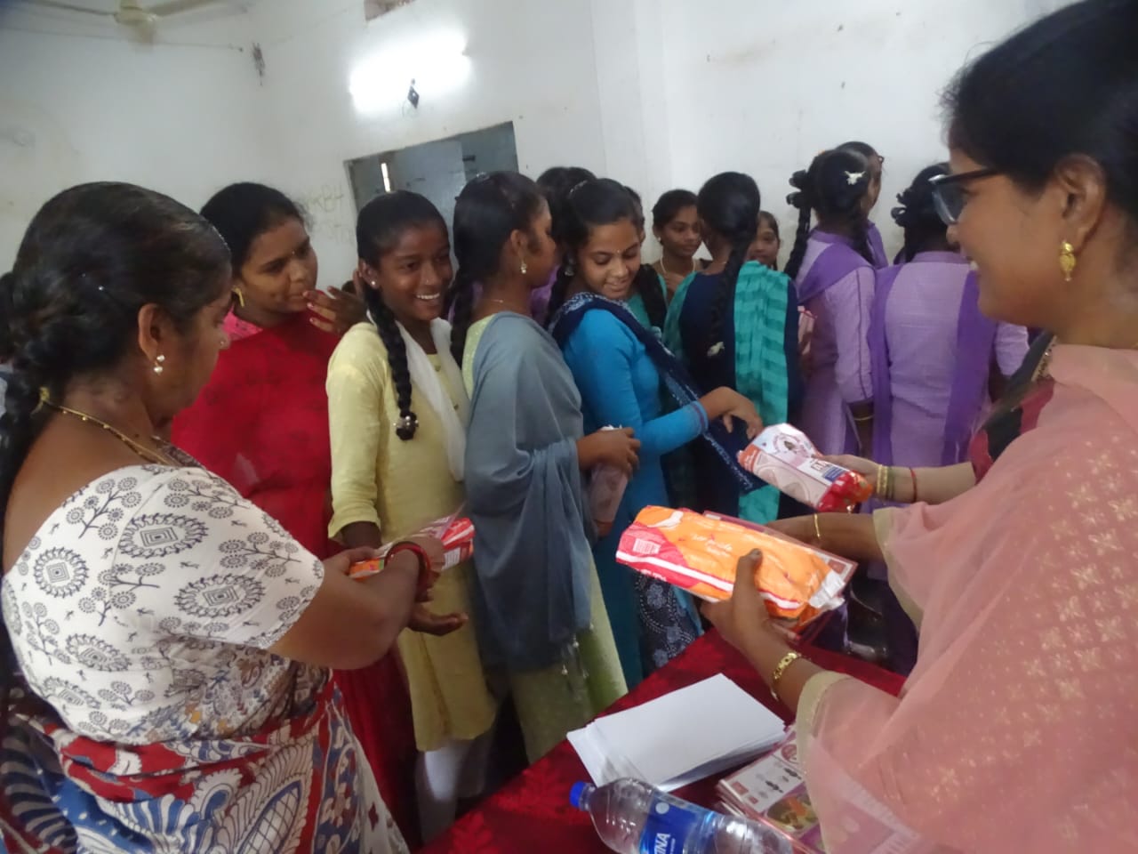 Eine indische Frau gibt Menstruationsbinden an Schulmädchen aus.