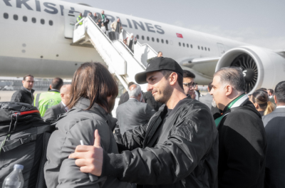 Serkan Eren steht mit vielen syrischen Männern vor einem Flugzeug von Turkish Airlines am Flughafen Damaskus in Syrien.